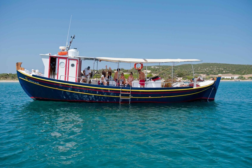 A colorful boat with people on board, anchored in calm waters with a clear sky and a hilly landscape in the background. 1