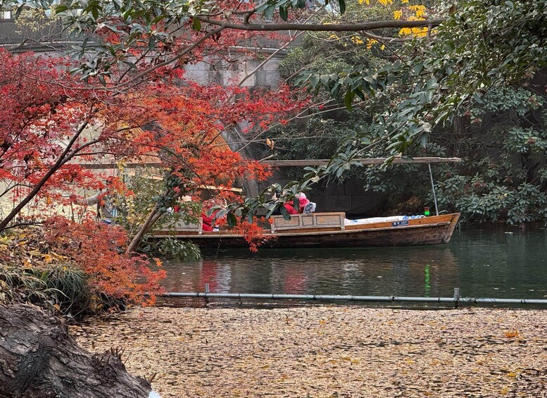 A wooden boat with passengers on a calm river, surrounded by autumn foliage. 2