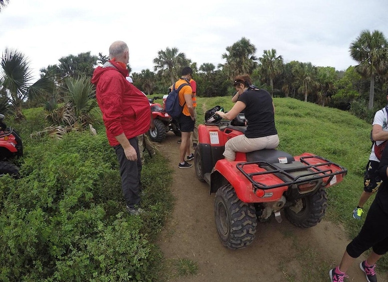 People on red ATVs on a dirt path surrounded by greenery. 3