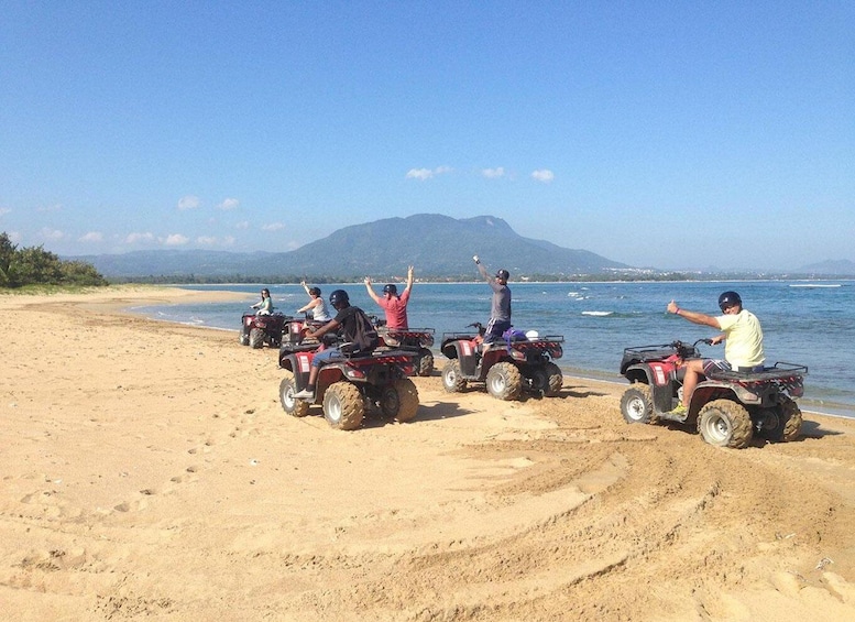 People on ATVs on a beach with a mountain in the background. 2
