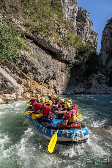 A group of people rafting down a river surrounded by rocky cliffs. 1