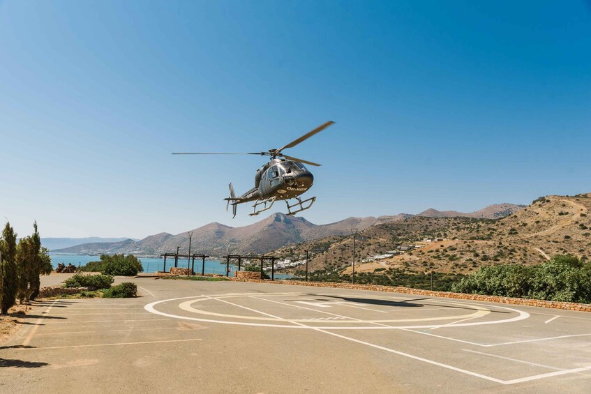 A helicopter hovering over a helipad with mountains and a body of water in the background. 2