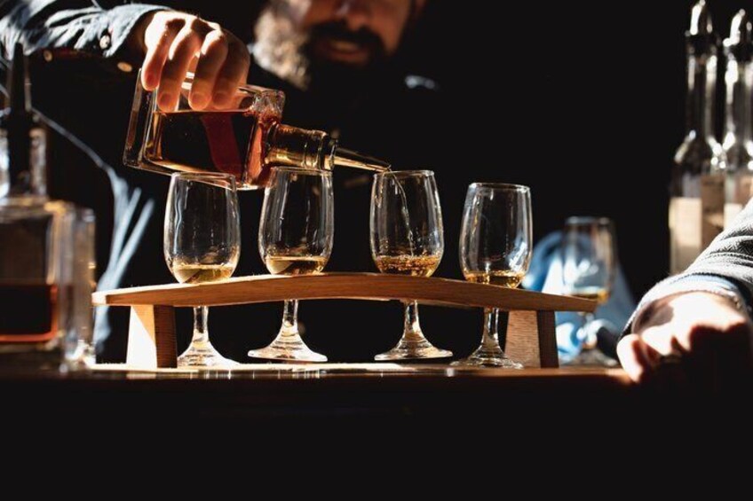 A person pouring a drink into a glass on a bar counter. 1
