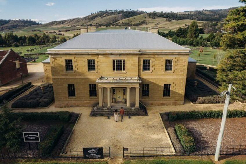 A large, historic building with a symmetrical facade, central entrance, and a well-maintained garden. 3