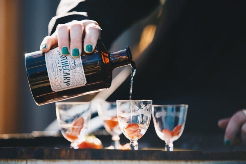A hand pouring a drink from a bottle into a glass. 5