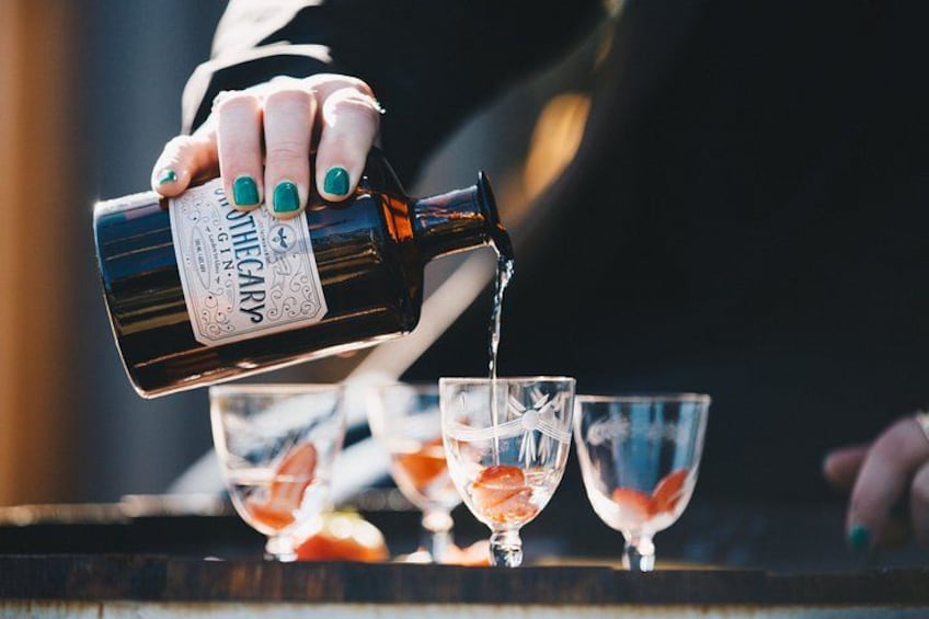 A hand pouring a drink from a bottle into a glass. 5