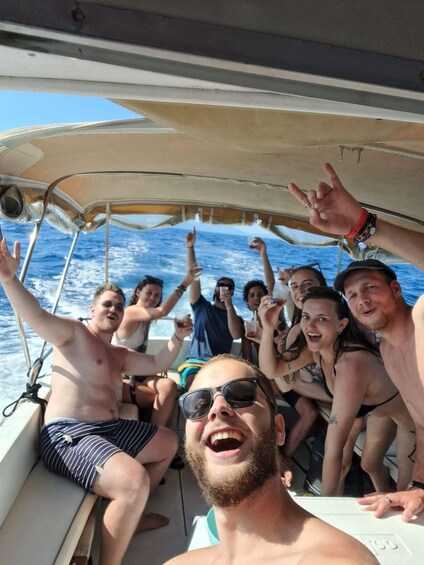 A group of people on a boat, some wearing swimwear, with the ocean in the background. 5