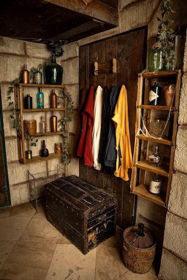 A rustic room with wooden shelves, a trunk, and hanging clothes. 2