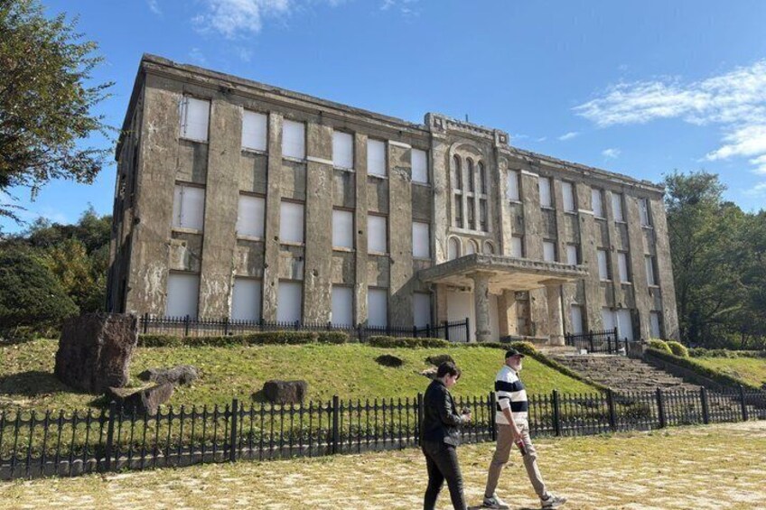 A large, historic building with a symmetrical facade, a central entrance, and a surrounding fence. 4