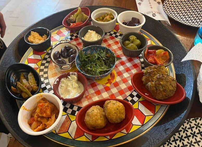 Ett färgstarkt fat med olika rätter, inklusive oliver, grönsaker och köttbullar. 5