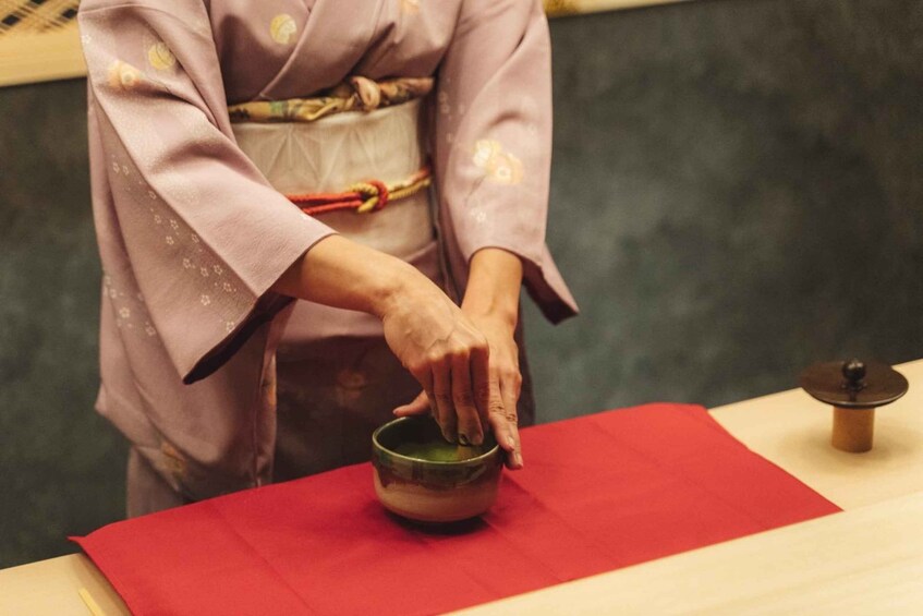 A person in traditional attire preparing a dish on a table with a red cloth. 5