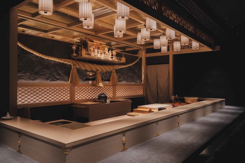 A modern kitchen with a long countertop, hanging lights, and decorative elements. 3
