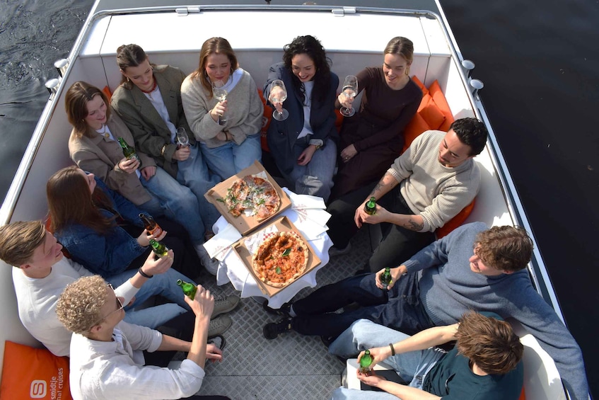 A group of people on a boat with pizza and drinks. 1