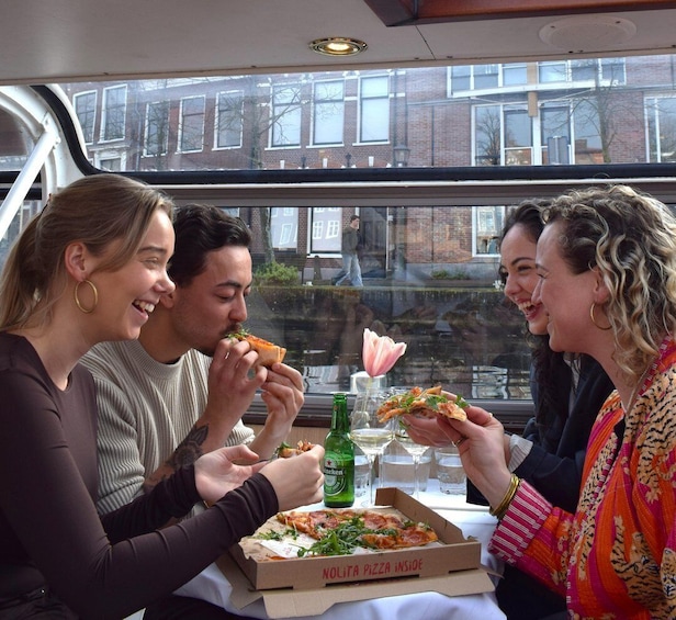A group of people sitting at a table inside a vehicle, eating pizza and drinking beer. 1