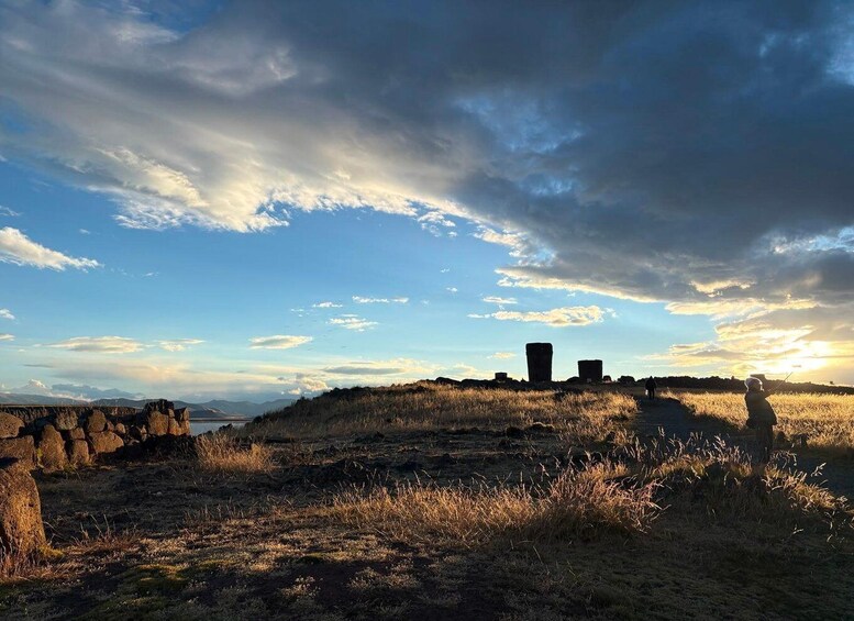 A coastal landscape with stone structures, a person fishing, and a sunset. 1