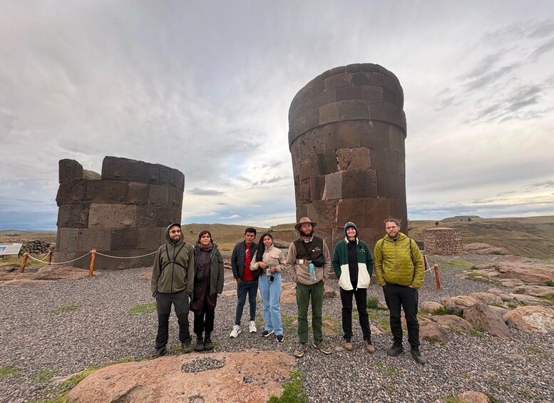 A group of people standing in front of a large stone structure with a cloudy sky in the background. 2