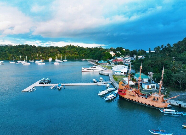 A harbor with multiple boats, a large ship, and a docked ship with masts. 5
