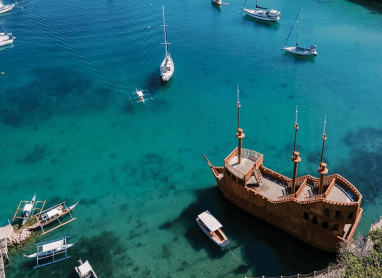 A large ship docked at a pier with several smaller boats in the background. 3