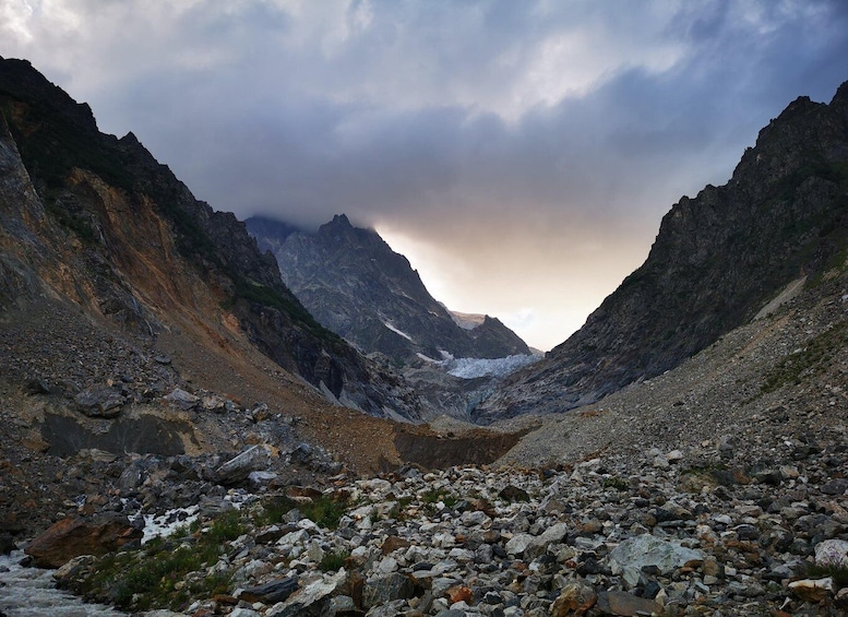 A rugged mountain landscape with a glacier and rocky terrain. 3
