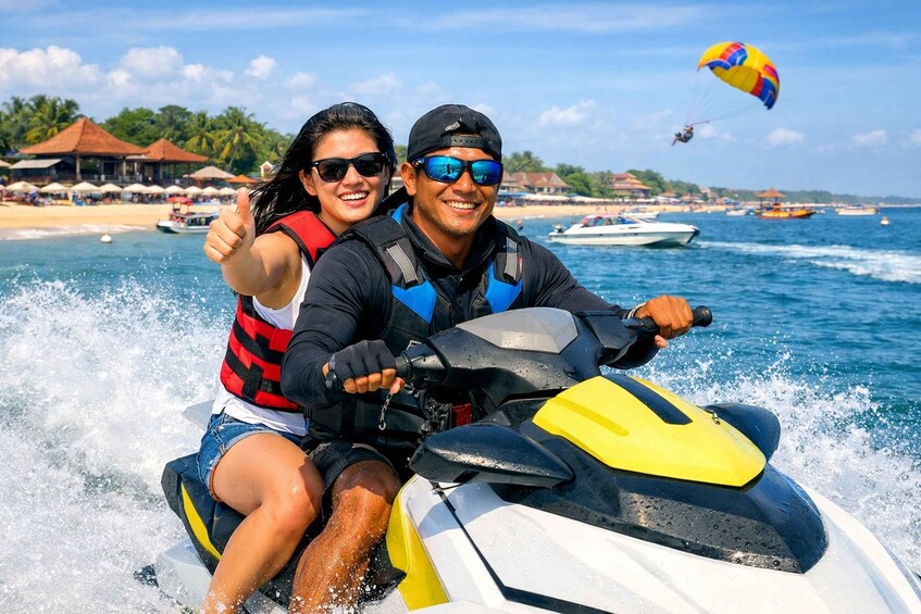 Two people on a jet ski with a parasail in the background. 4
