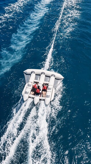 A jet ski with four people wearing life jackets, riding on a wake. 5