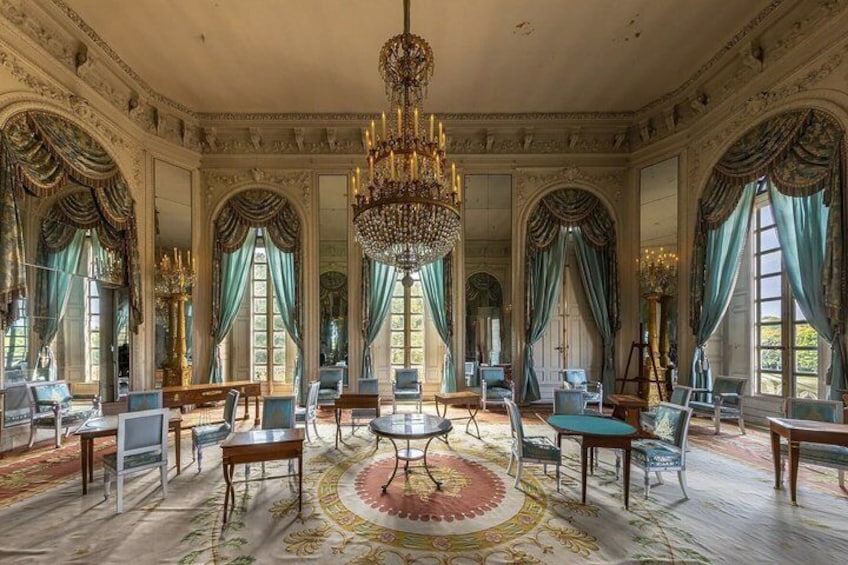A grand room with ornate chandeliers, large windows with draped curtains, and elegant furniture. 2