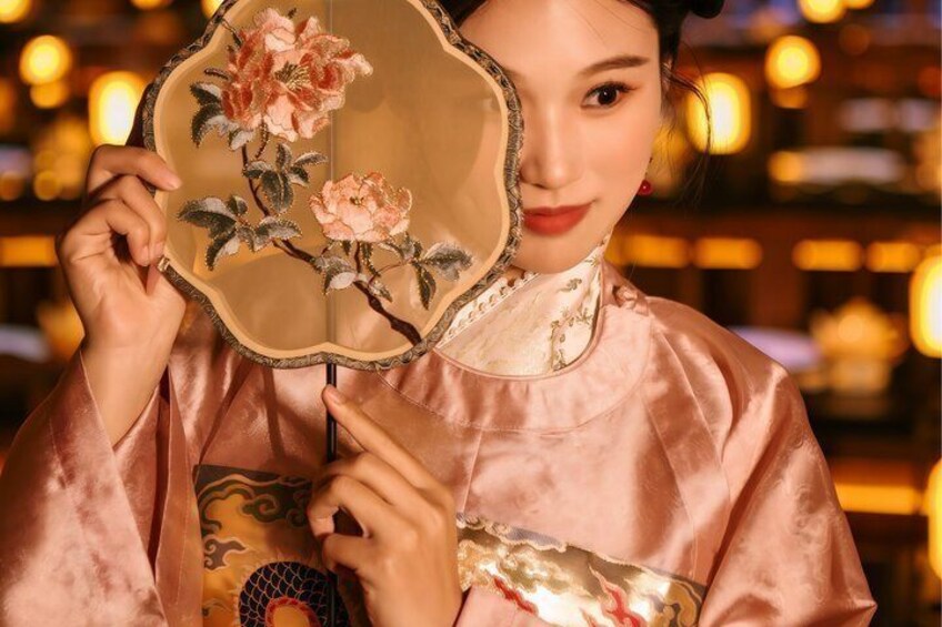 A person holding a traditional fan with floral embroidery. 5