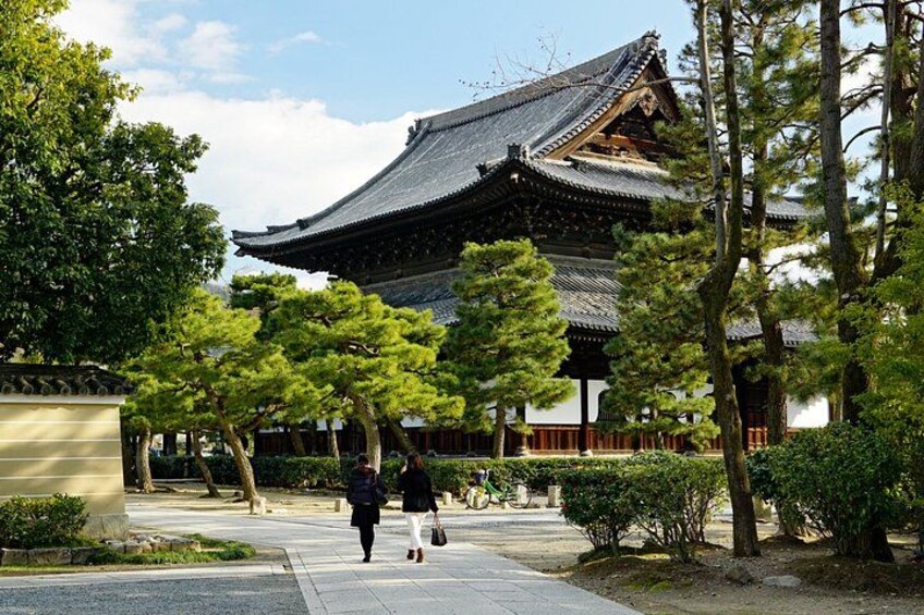 A traditional Japanese building with a tiled roof, surrounded by trees and a paved walkway. 3