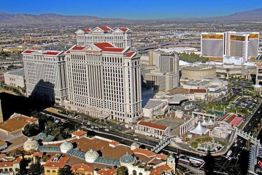 A large white building with a red roof, surrounded by other buildings and a river. 5