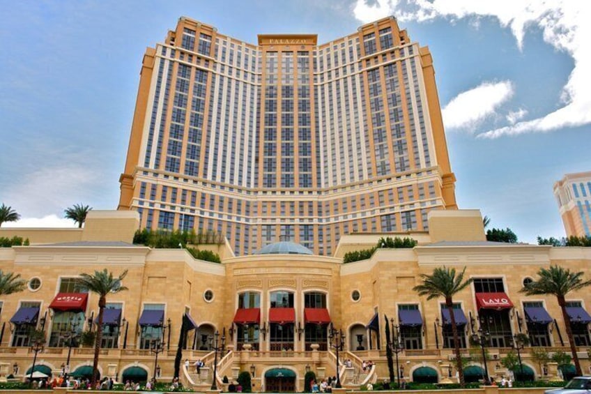 A large, multi-story hotel with a central atrium, palm trees, and a clear sky. 2