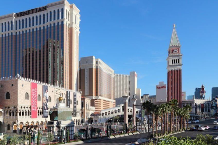 The Venetian hotel, a tall building with a clock tower, and the nearby street with palm trees. 3