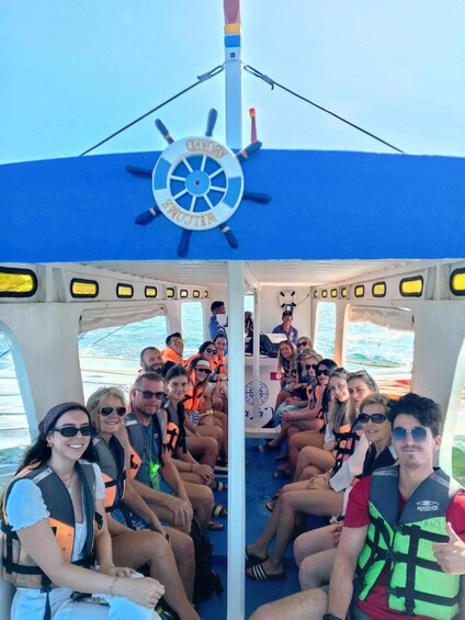 A group of people on a boat with a steering wheel marked 'WELCOME' and life jackets. 3
