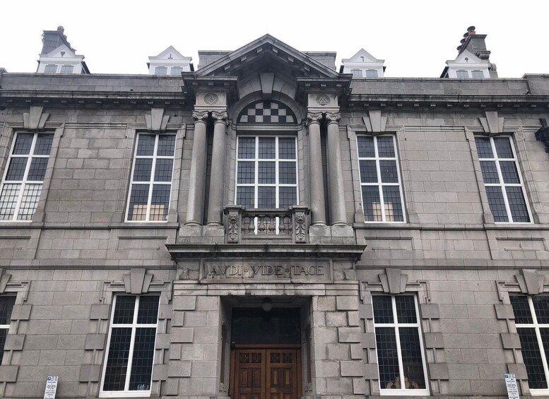 A historic building with a central entrance, flanked by columns and a decorative pediment. 3