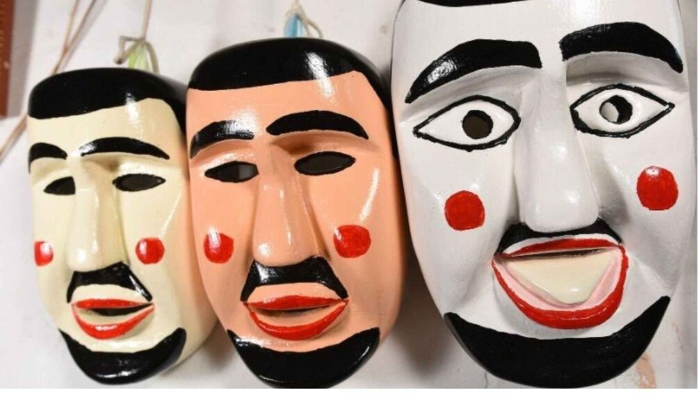 Three masks with distinct facial features and colors. 1