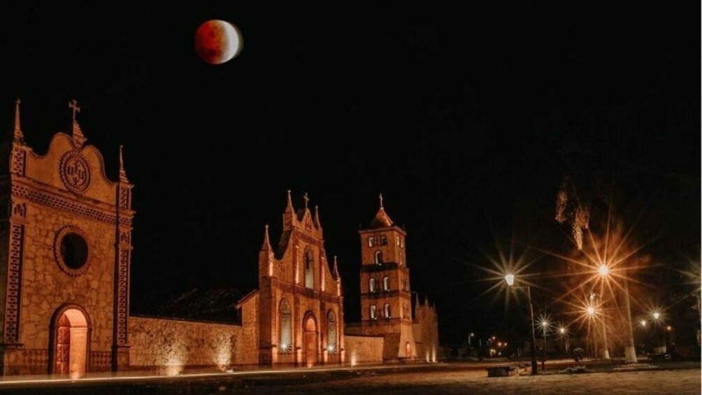 A historic church with Gothic architecture, a large moon, and street lamps. 3