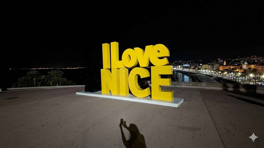 A large yellow sign with the words 'I Love Nice' against a night cityscape backdrop. 5
