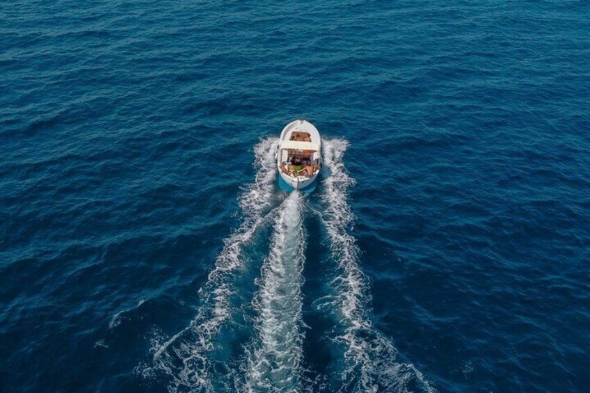 A boat moving through a deep blue sea, leaving a wake behind. 2