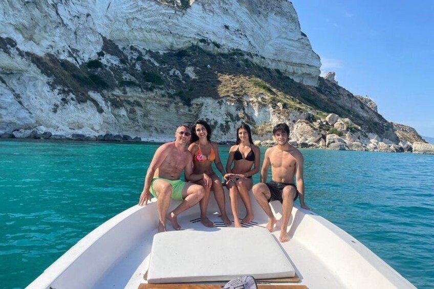 A group of people on a boat with a rocky coastline in the background. 4