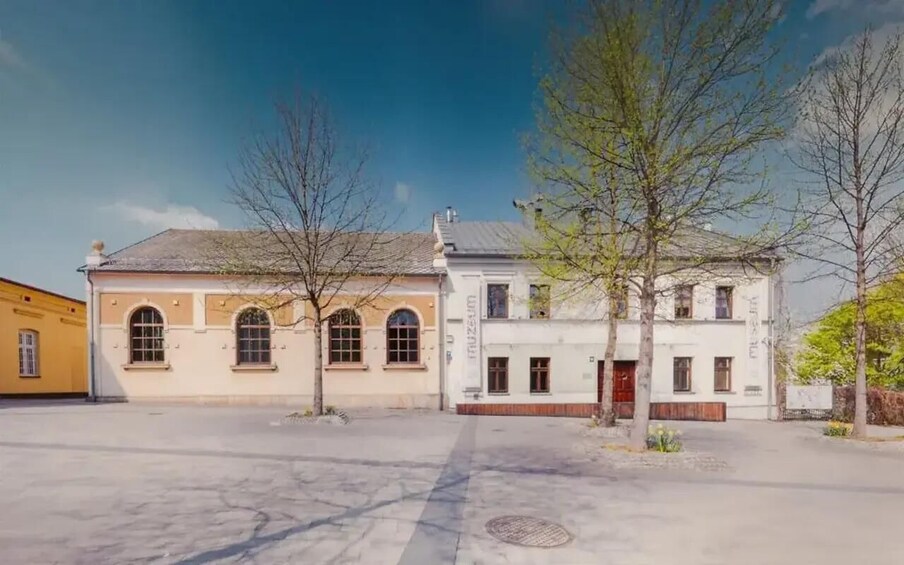 A street with two-story buildings, a clear sky, and leafless trees. 1