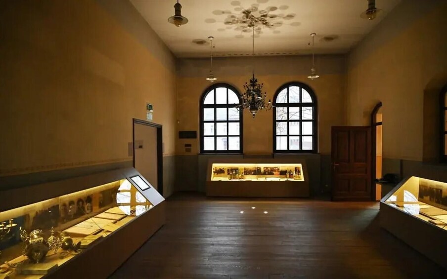 An interior with arched windows, a chandelier, and display cases. 2