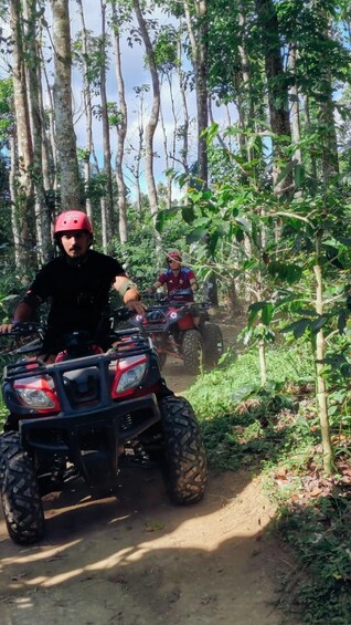 Two people riding ATVs on a dirt path through a forest. 5