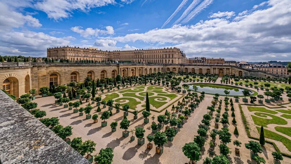 A grand palace with symmetrical gardens and a large fountain. 2