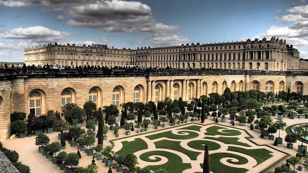A grand palace with a symmetrical garden featuring geometric patterns and neatly trimmed hedges. 5