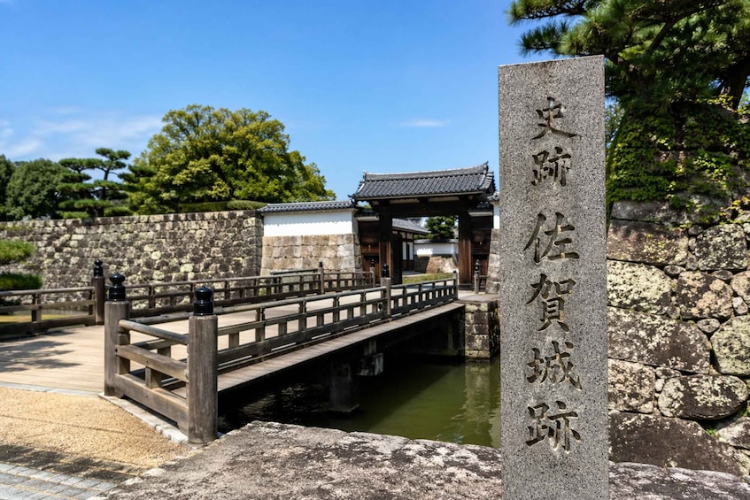 A stone bridge over water, traditional Japanese architecture, and a stone wall. 2