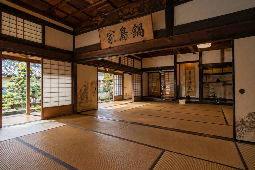 A traditional Japanese room with tatami flooring, sliding doors, and a sign with Japanese characters. 5