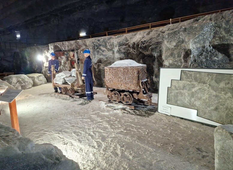 A museum exhibit with a model of a mining cart and two figures in blue uniforms. 3