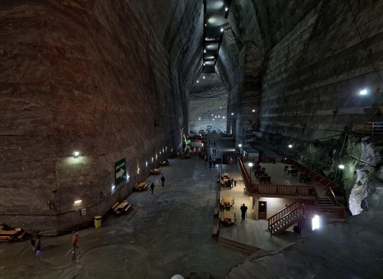 An underground cavern with high ceilings, stone walls, and a central walkway. 1