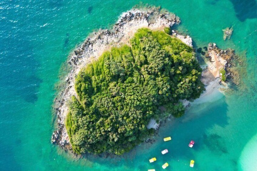 An aerial view of a small island with dense green vegetation surrounded by turquoise waters. 4