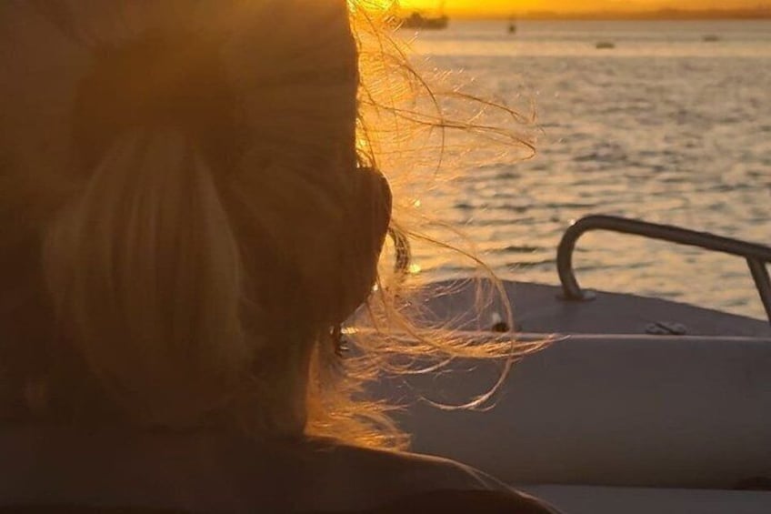 A boat with a person in the foreground and a sunset over the water. 2