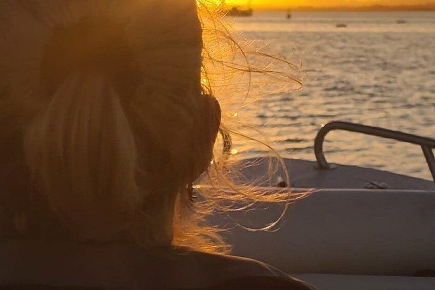 A boat with a person in the foreground and a sunset in the background. 2
